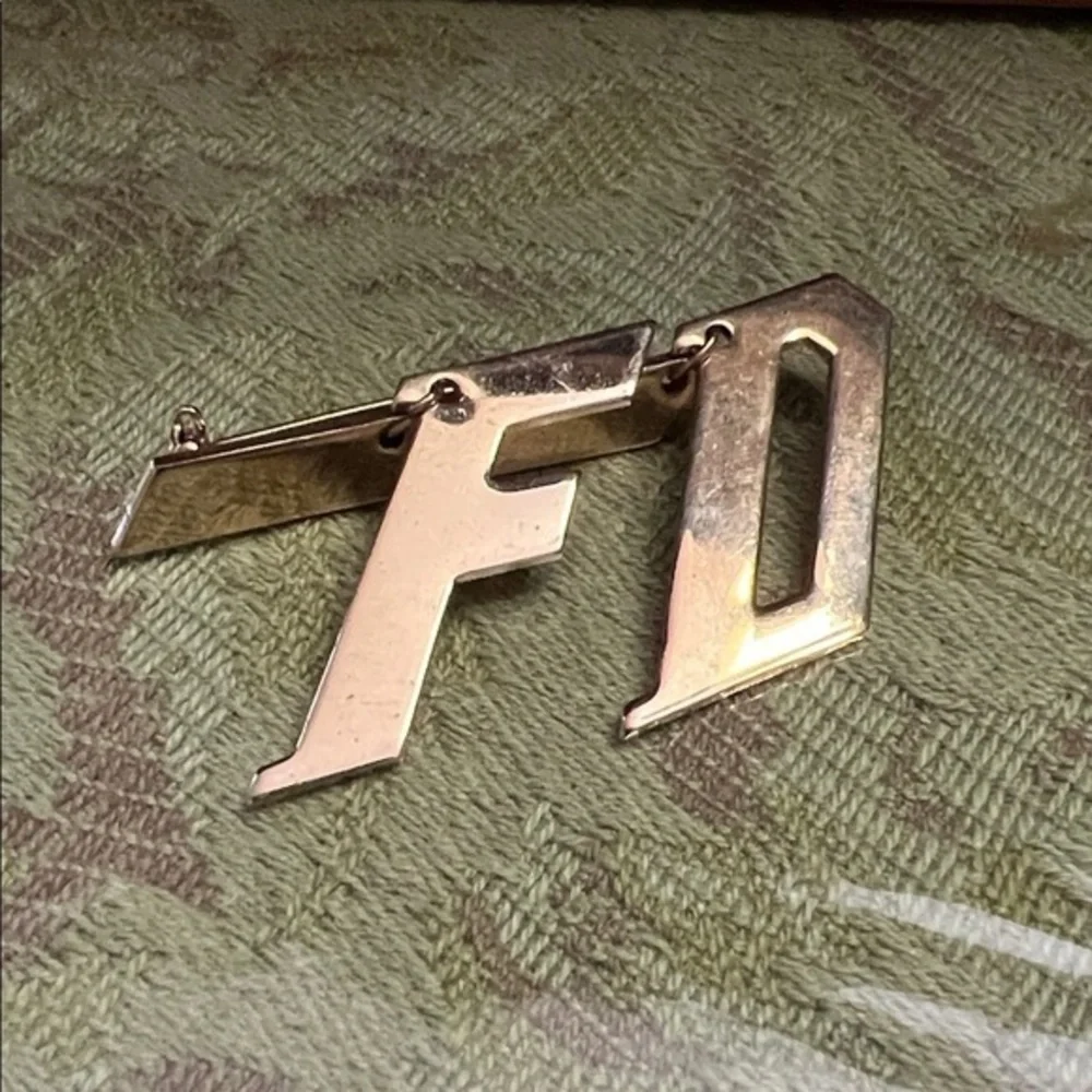 This is a gold tone, FD lapel, or collar pin, which stands for fire department